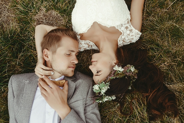 bride and groom lying on grass