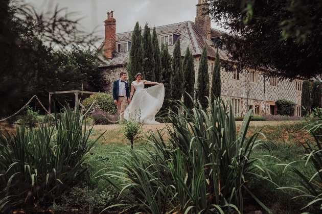 Bride and groom walking through the gardens of Manor Estate in front of the House