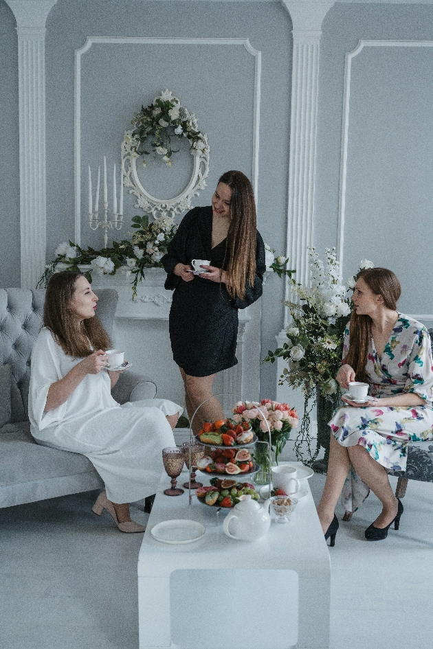 bride sits down at a bridal boutique with her maid of honour and bridal consultant enjoying refreshments