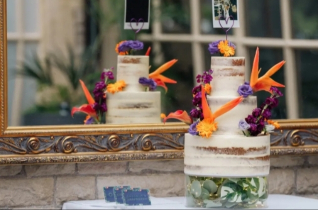 three teir semi naked wedding cake decorated with orange and purple flowers