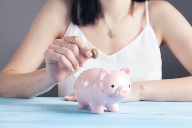 woman putting pound in her piggy bank