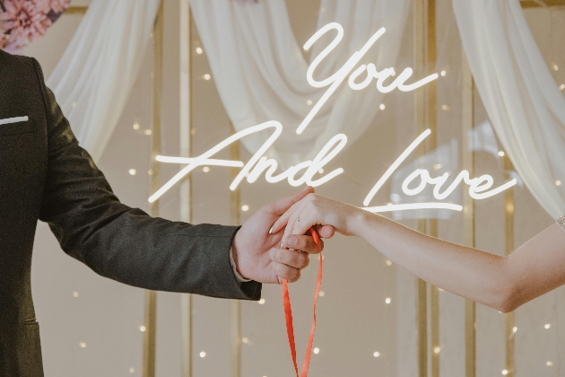wedding handfasting with you and love neon sign in background