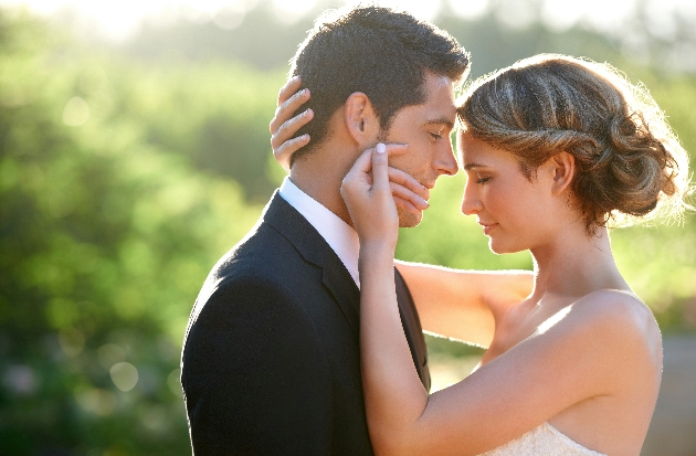 bride and groom in halo of natural light, bride brushes groom's cheek