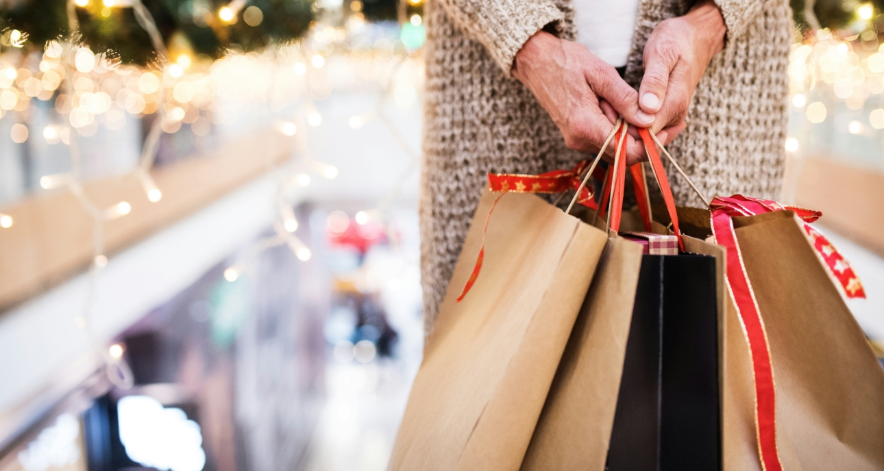 woman holding christmas shopping bags with fairylights in the background