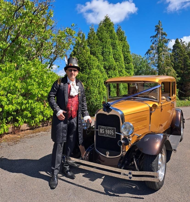 Arriving in Style founder next to one of his cars dressed in Steampunk style