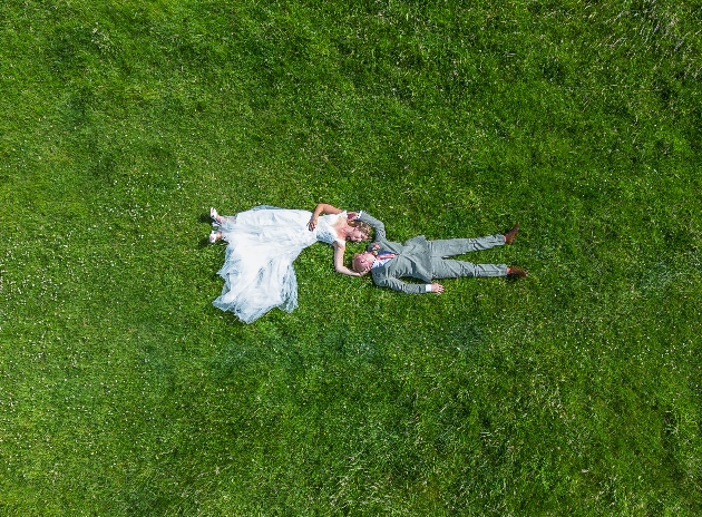 bride and groom seen from overhead lying on the grass