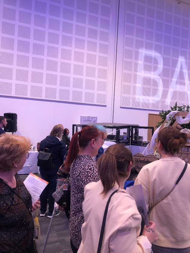 Group of people gathered around a stand at a wedding show