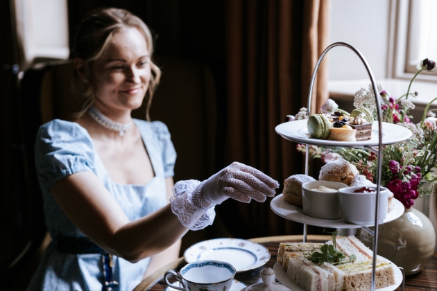 Woman dressed in blue regency attire enjoying an afternoon tea at The Gainsborough Bath Spa