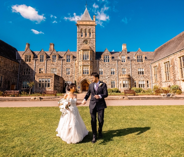bride and groom walking hand in hand with Taunton School in the background